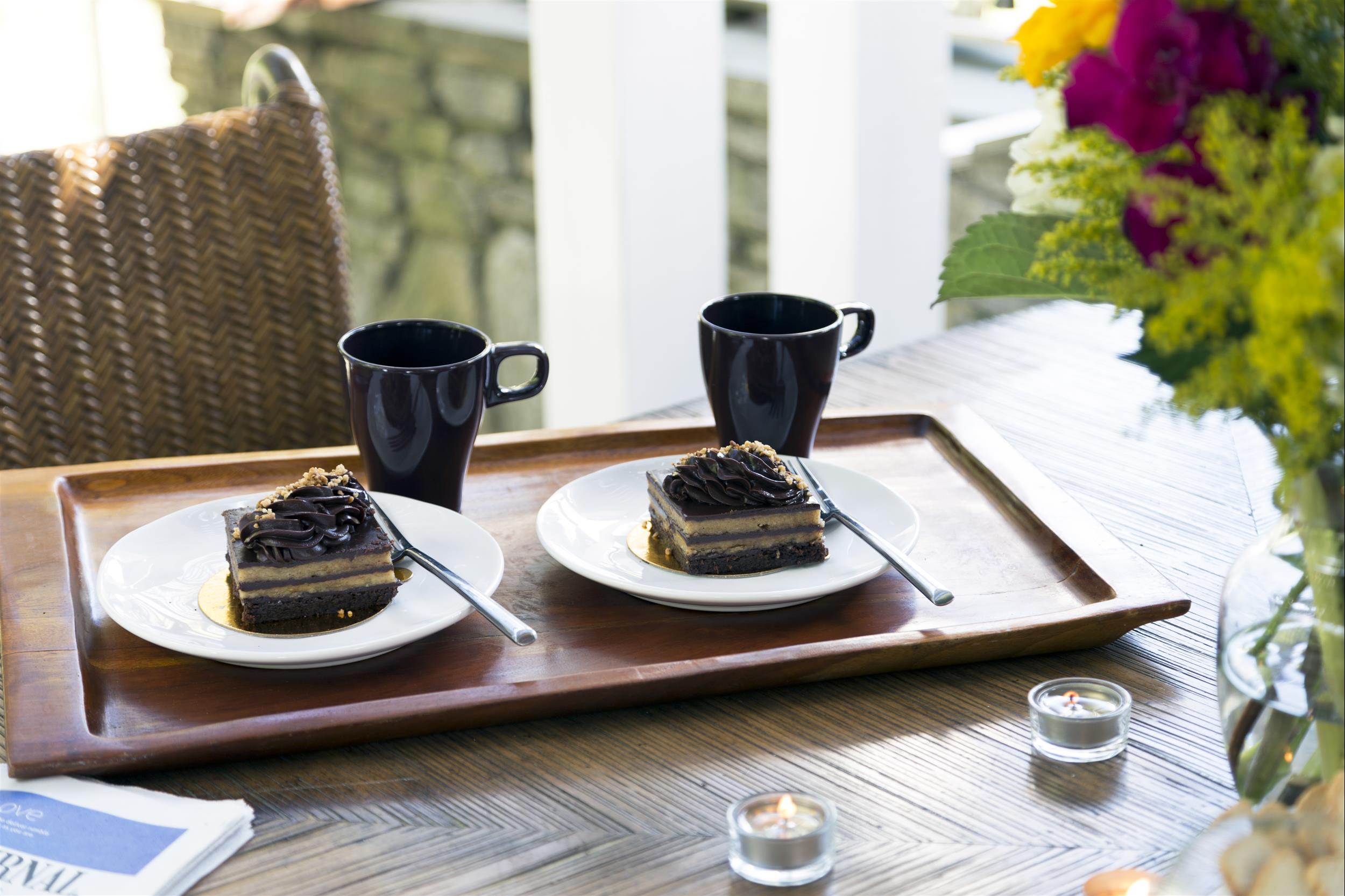 Two pieces of cake and coffee mugs on a serving tray